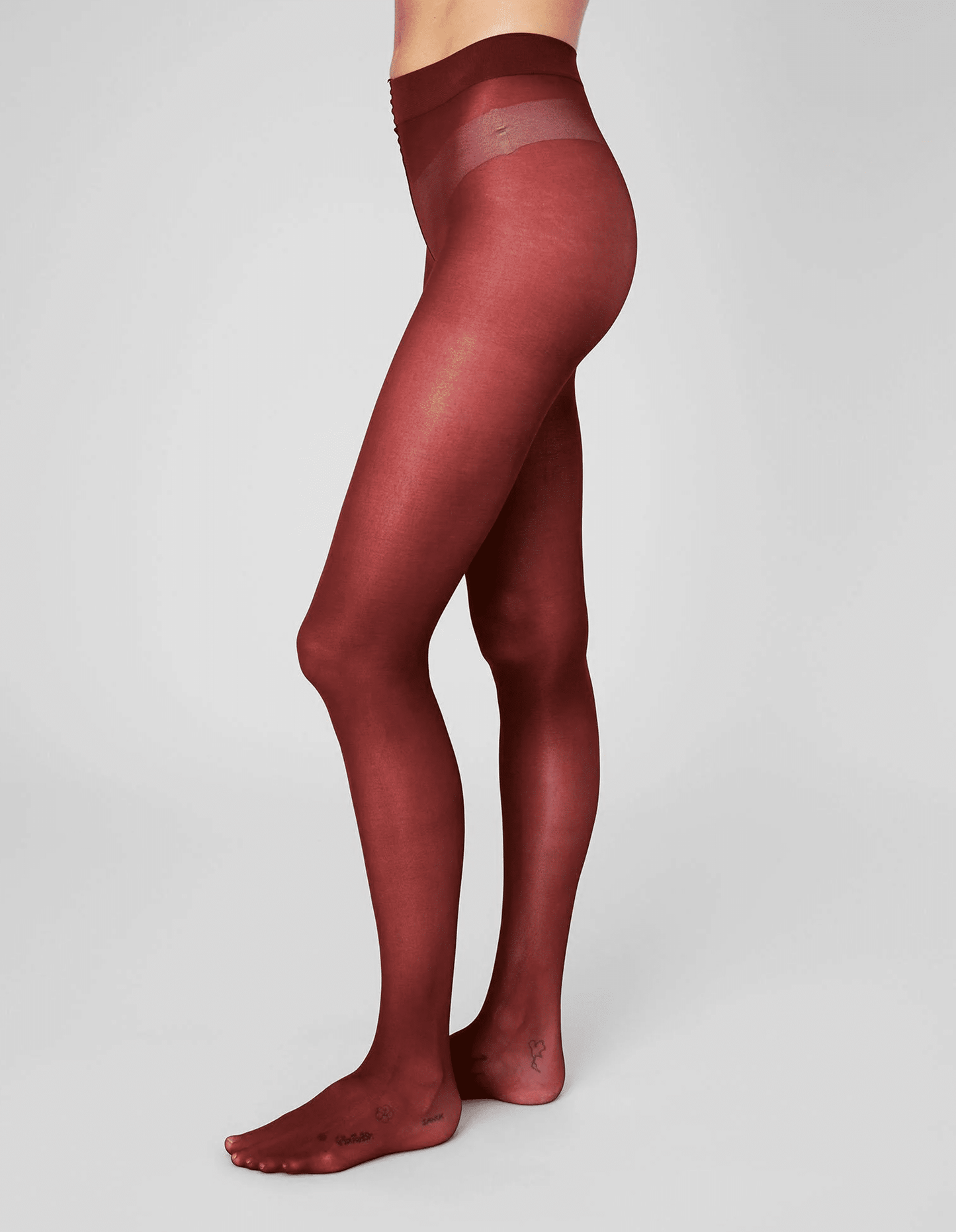 Red sheer tights worn by a person on a light gray background
