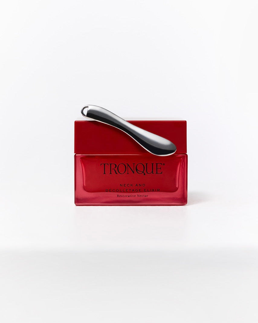 A red rectangular cosmetic jar with a metallic silver curved applicator resting on top, labeled TRONQUE on the front, set against a clean white background.
