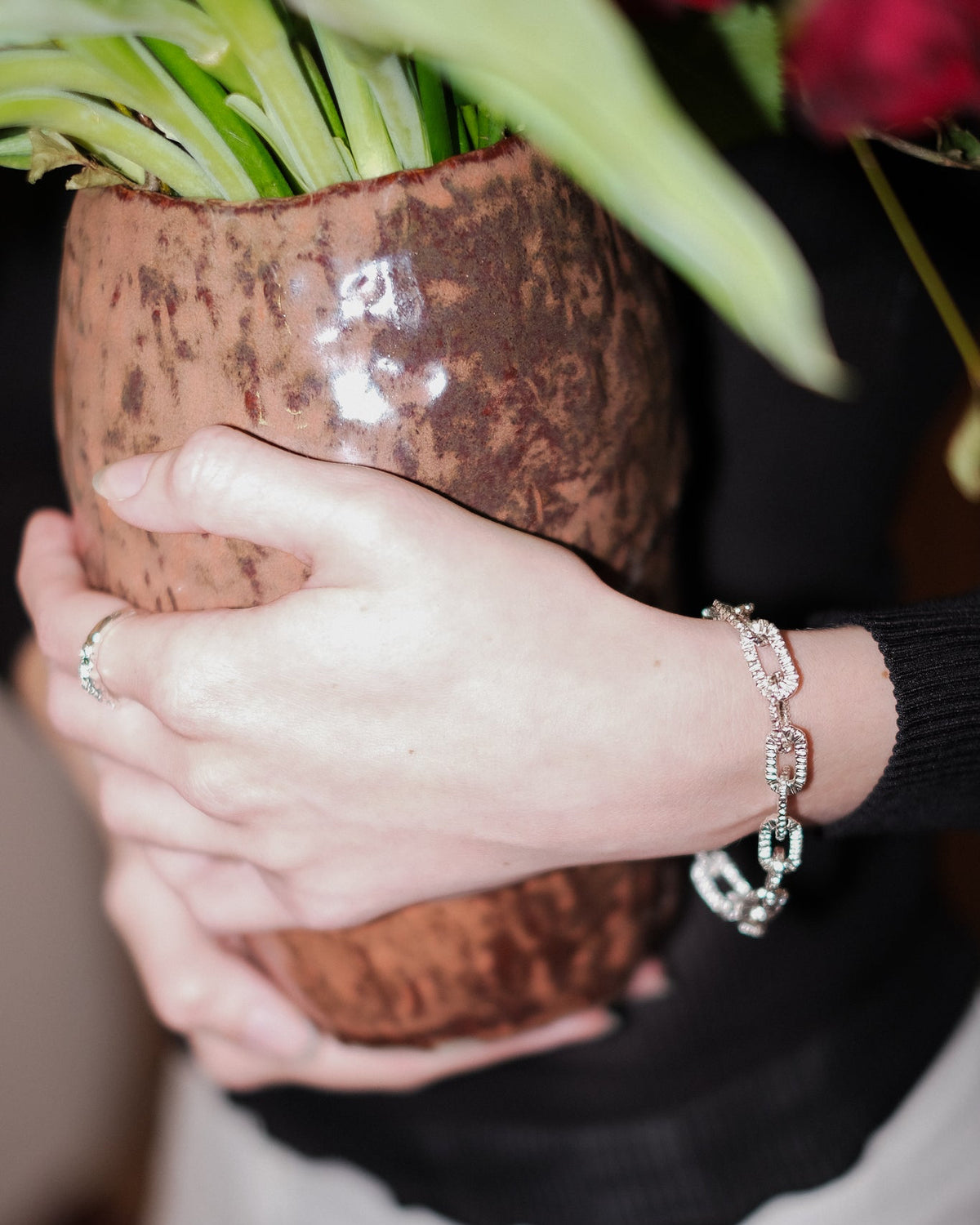 Front view of Alexandra Dodds Teeth Chain Link Bracelet on model’s wrist, holding a vase.