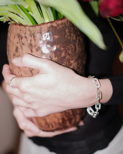 Front view of Alexandra Dodds Teeth Chain Link Bracelet on model’s wrist, holding a vase.
