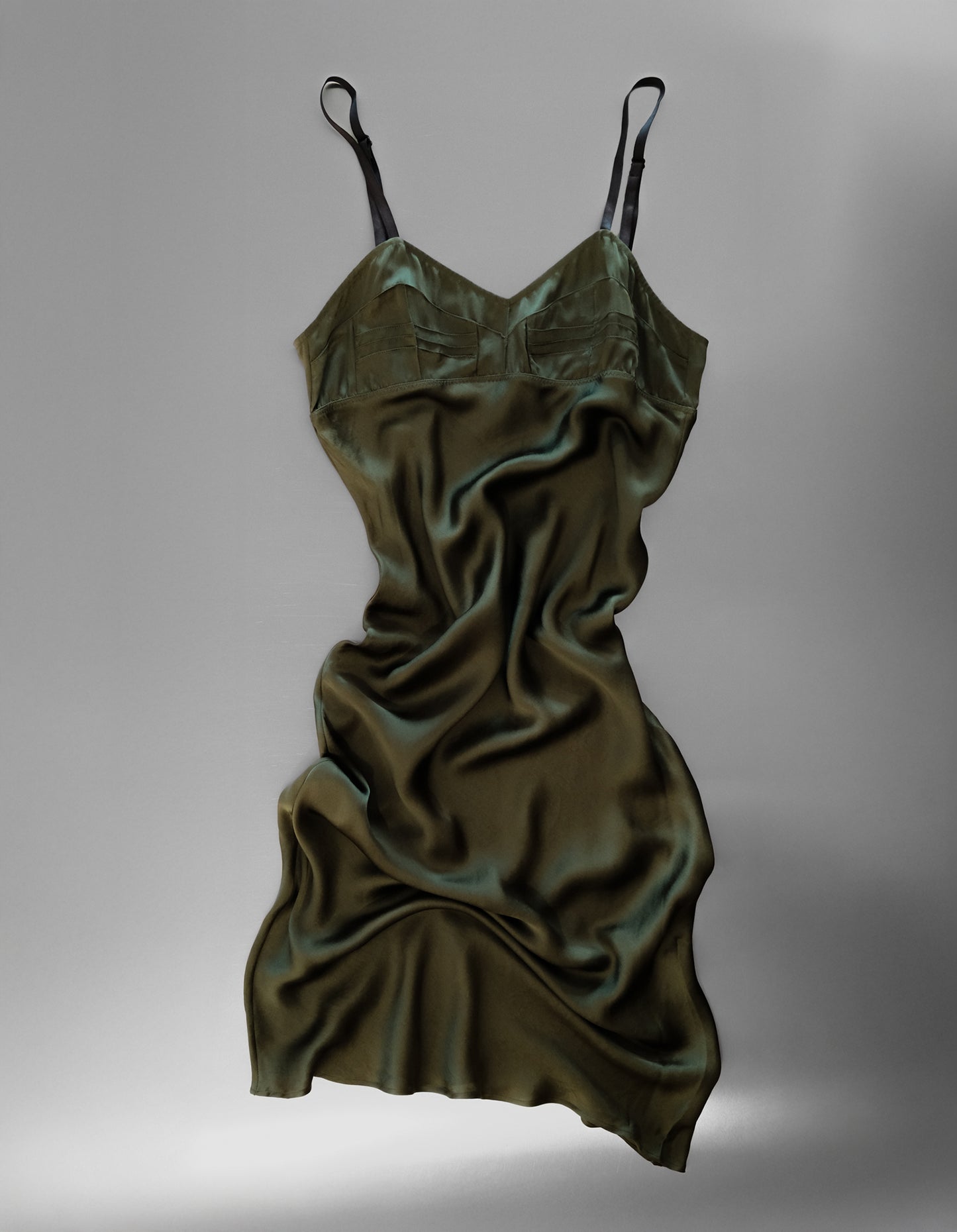 Green satin slip dress on a gray background