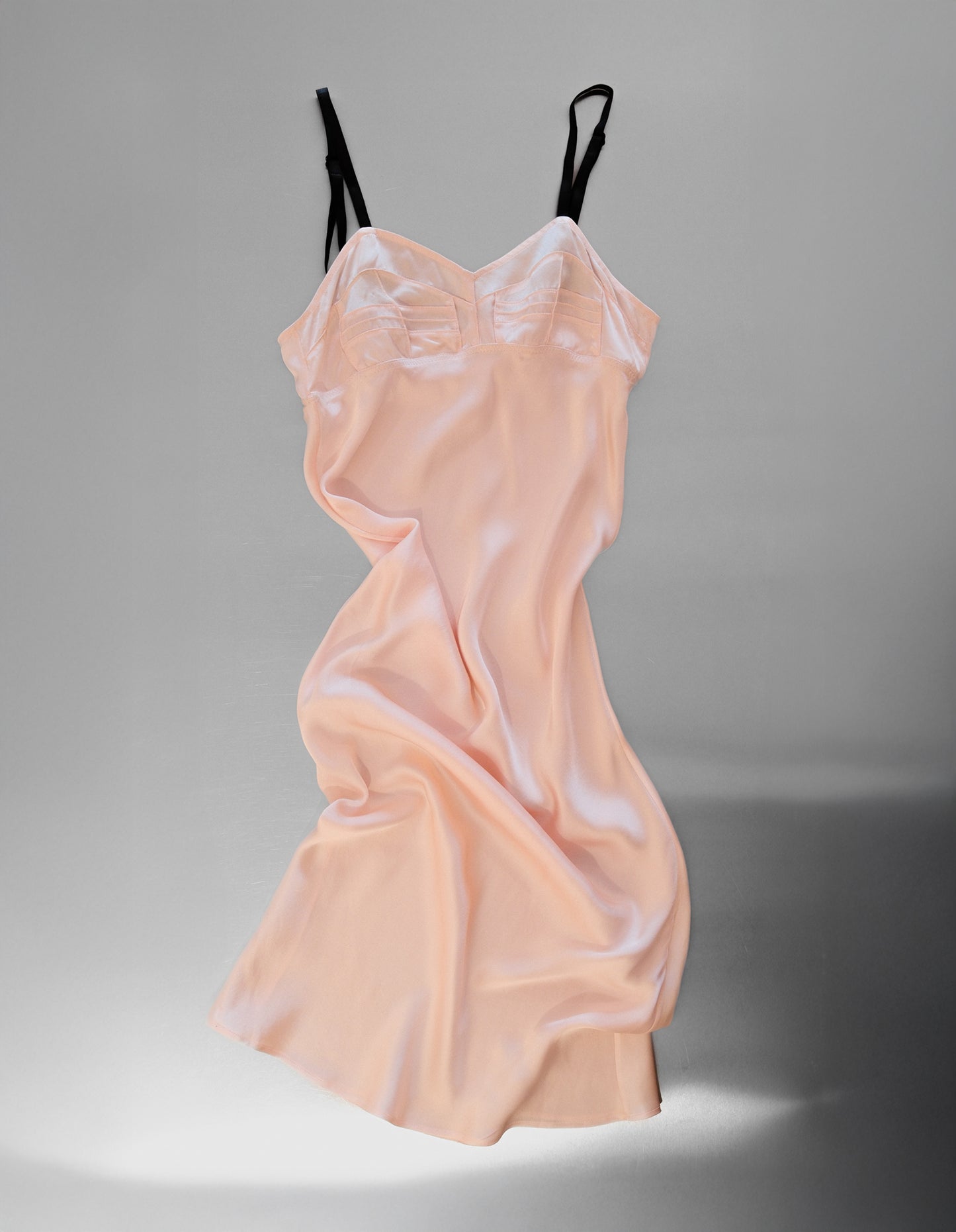 Pink slip dress with black straps on a gray background