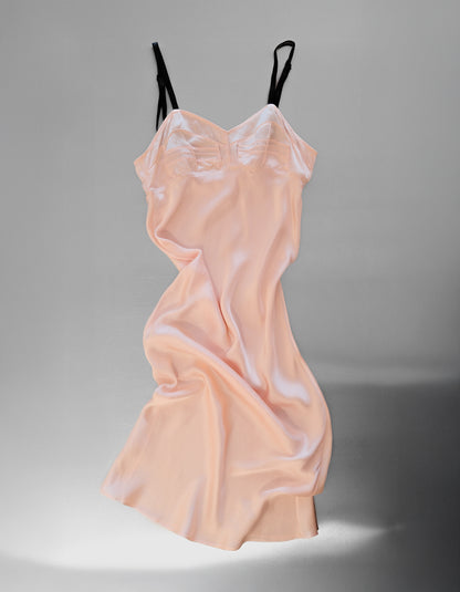 Pink slip dress with black straps on a gray background