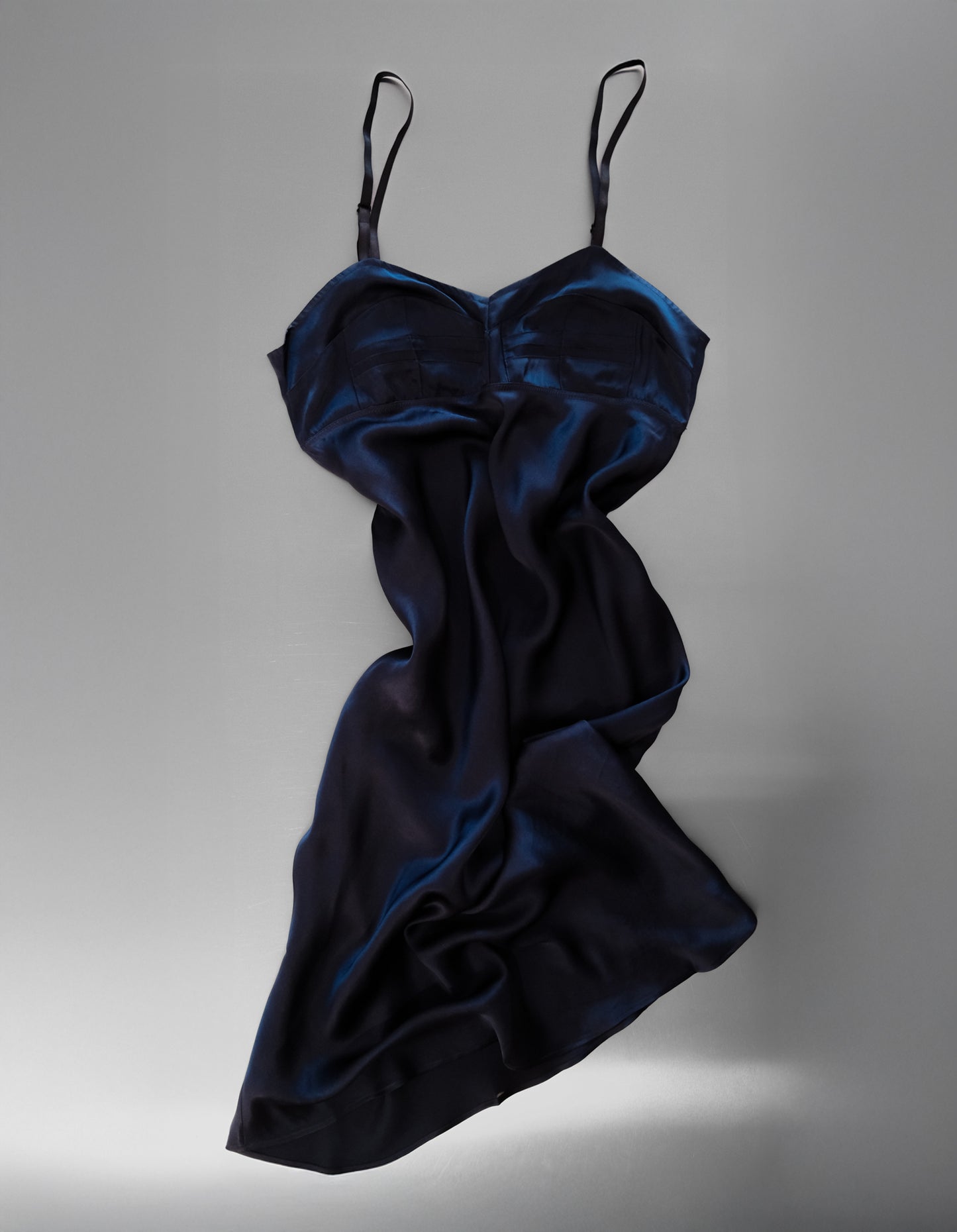 Navy blue satin slip dress on a gray background