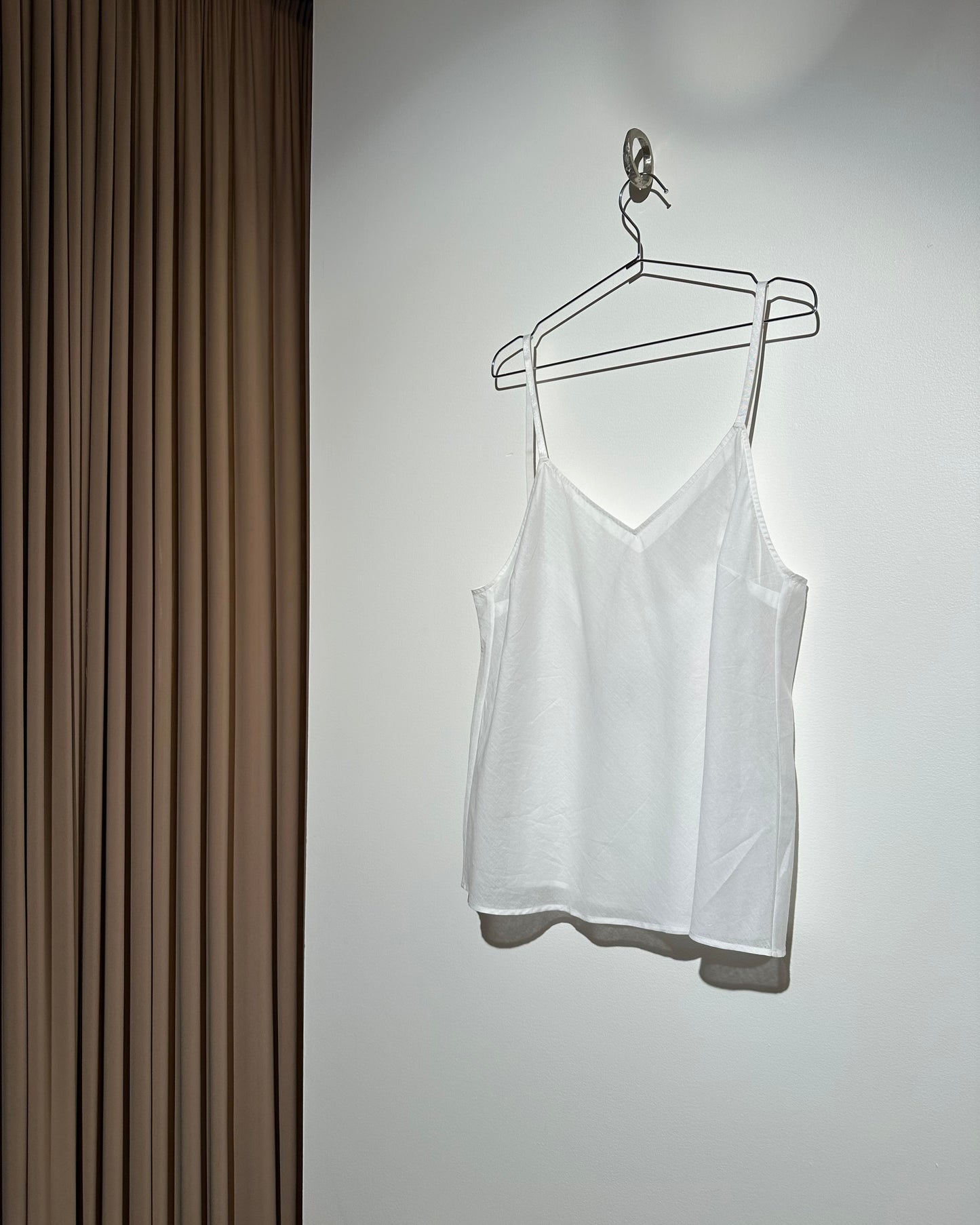 White dress on a hanger against a white wall with a wooden floor.