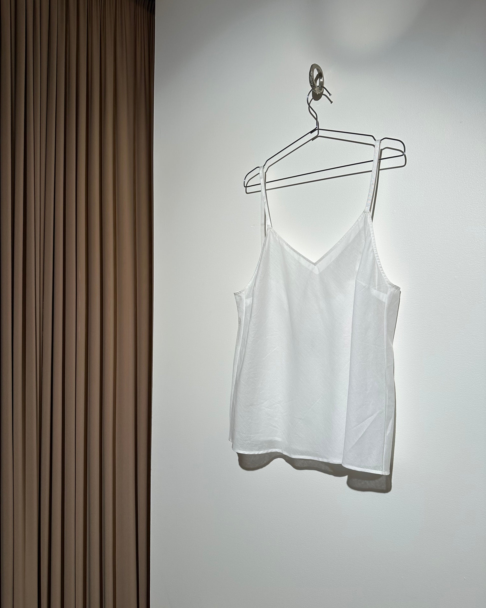 White dress on a hanger against a white wall with a wooden floor.