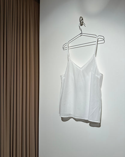 White dress on a hanger against a white wall with a wooden floor.