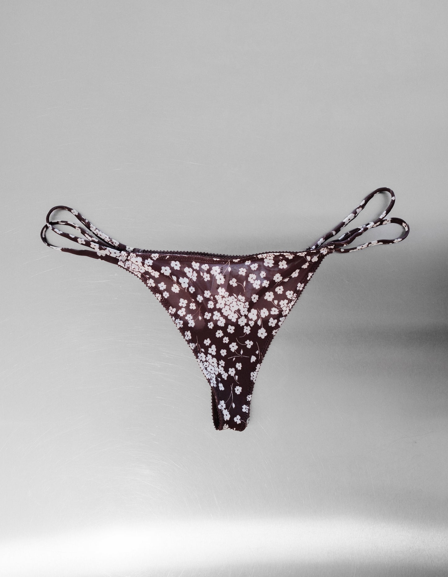 Floral-patterned mesh thong on a gray background