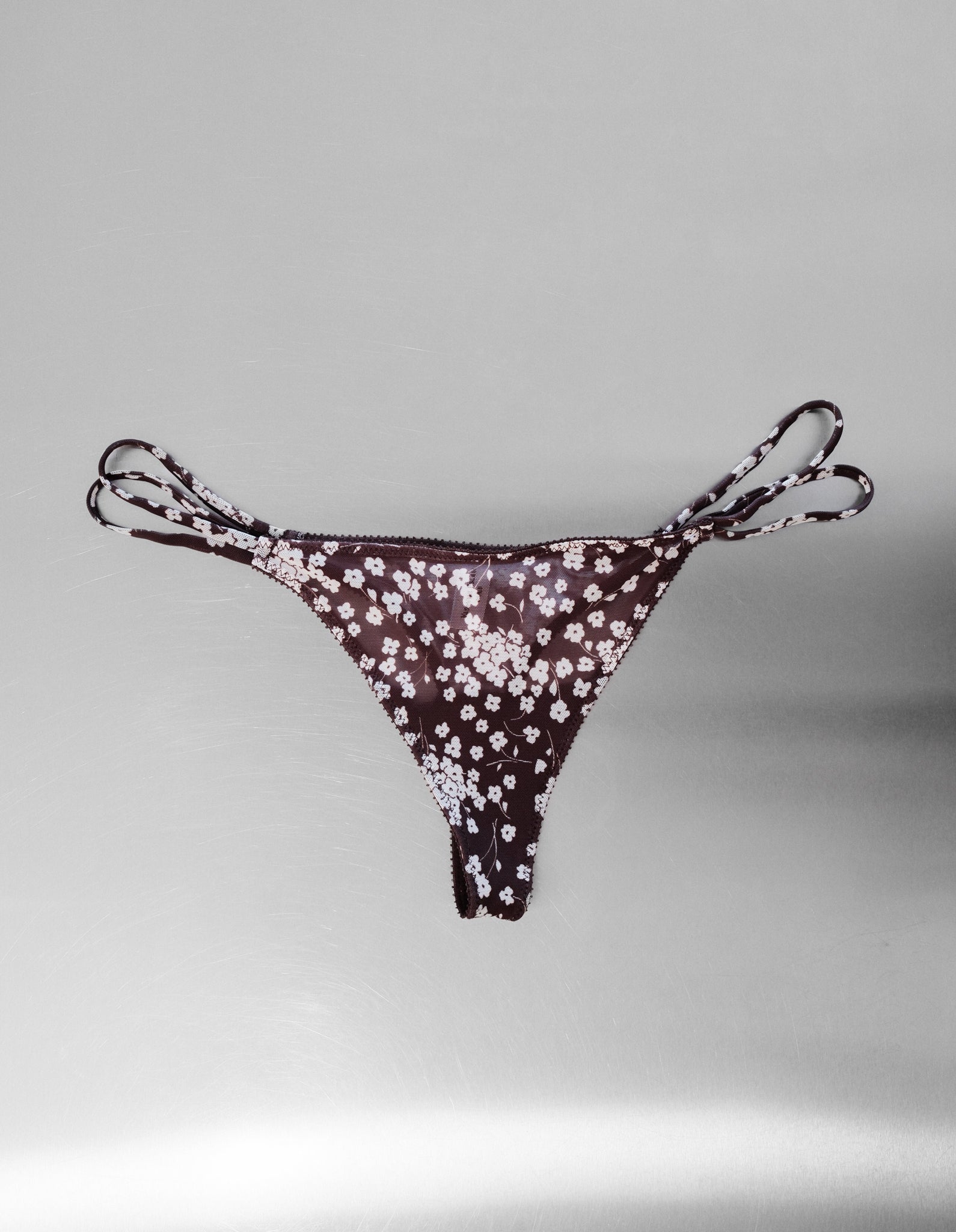 Floral-patterned mesh thong on a gray background