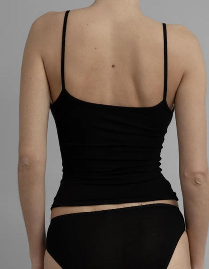 Person wearing a black tank top and black underwear on a gray background