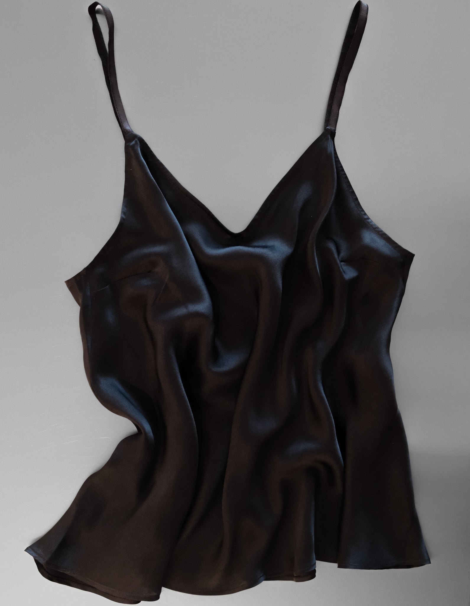 Black satin slip dress on a gray background